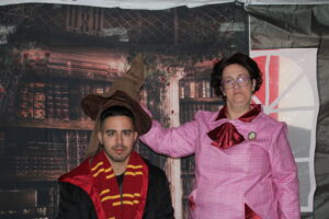 Imagen del Fotocall sombrero seleccionador con un chico que le ponen el sombrero, va con la tónica de Gryffindor. Le está poniendo el sombrero una mujer vestida de Dolores Umbridge