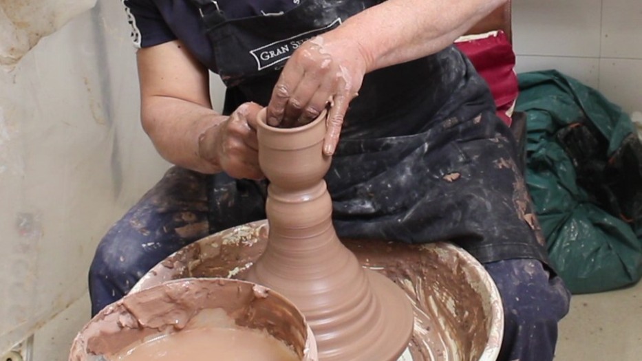 El alfarero está moldeando el barro para formar una taza de cerámica